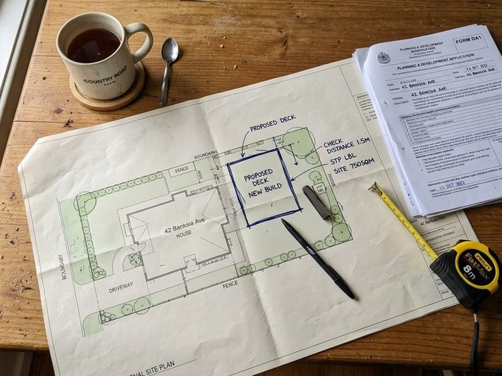 Building plans and paperwork spread out on a kitchen table
