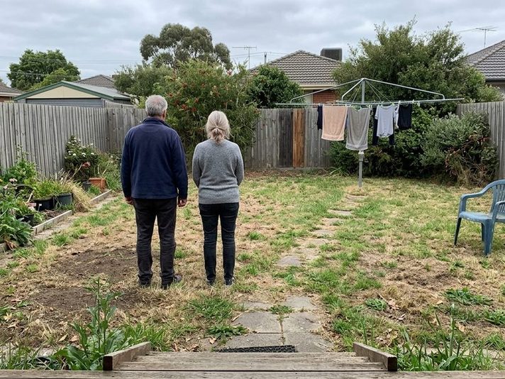 A couple looking at a tired back yard before selling