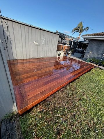 Freshly oiled merbau deck beside a shed