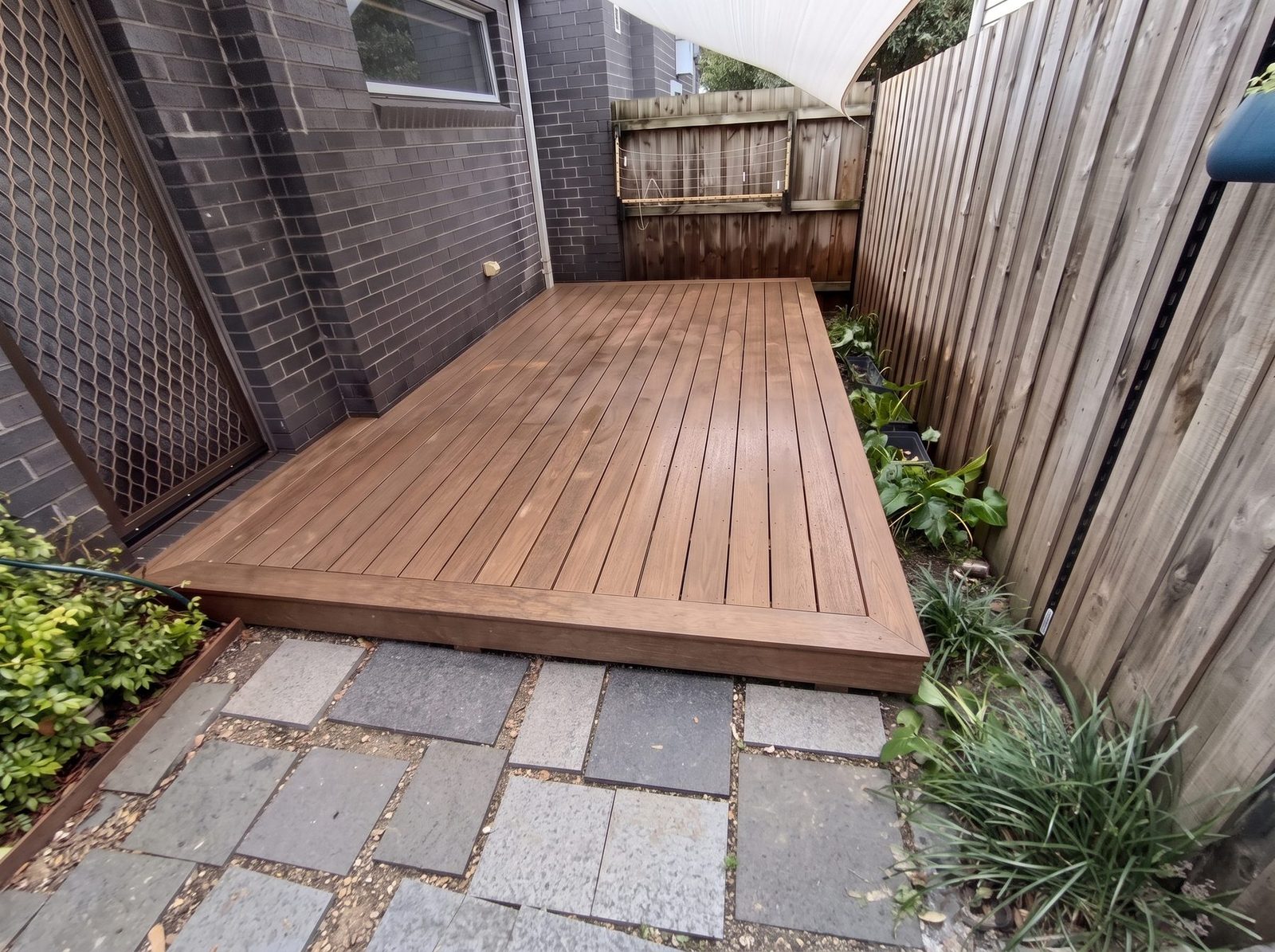 Merbau deck filling a narrow courtyard between a house wall and a fence